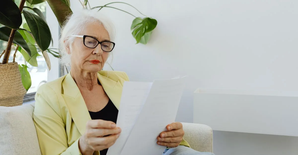 Portrait d'une femme d'affaires senior en blazer lisant des documents à l'intérieur.