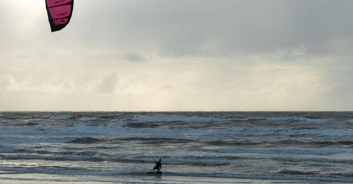 Un kitesurfeur glissant sur les vagues à la plage d'Amsterdam par temps nuageux.