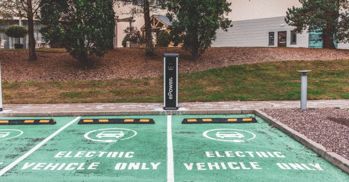 Stationnement de véhicules électriques verts avec borne de recharge en milieu urbain.